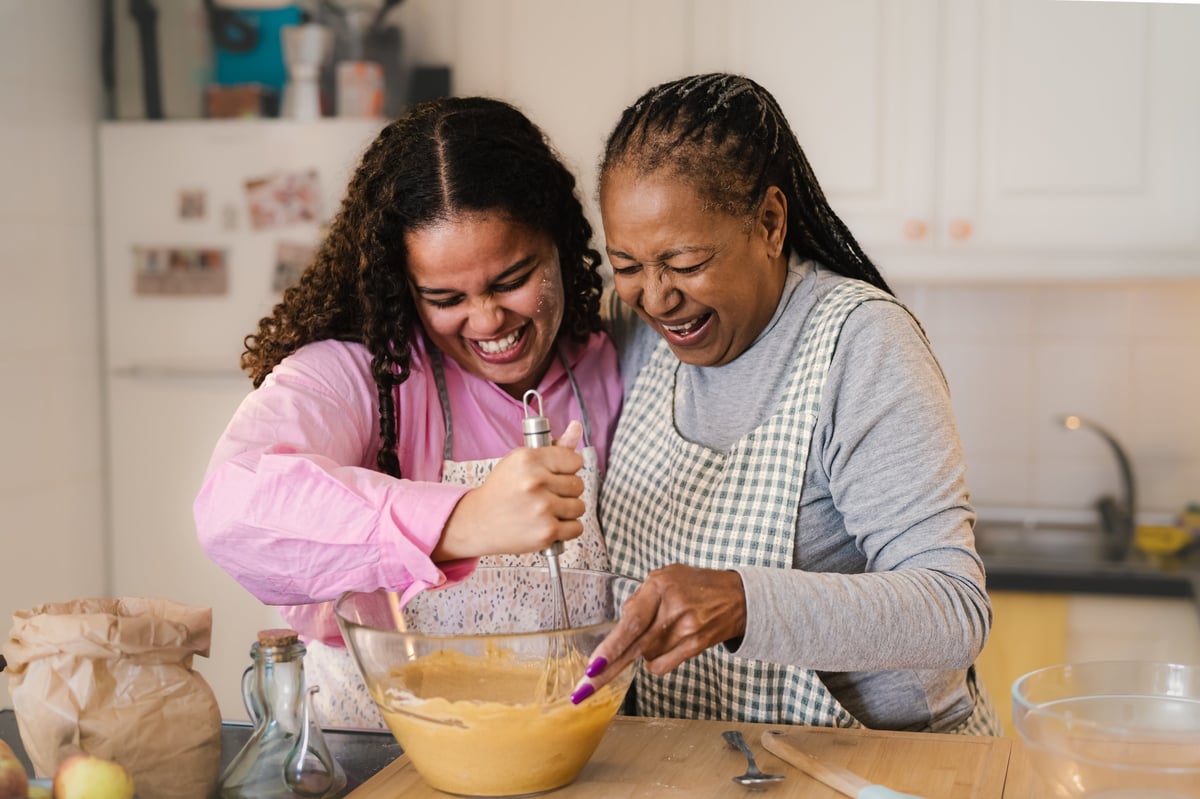 A mother and her daughter happily preparing a homemade dessert together at home